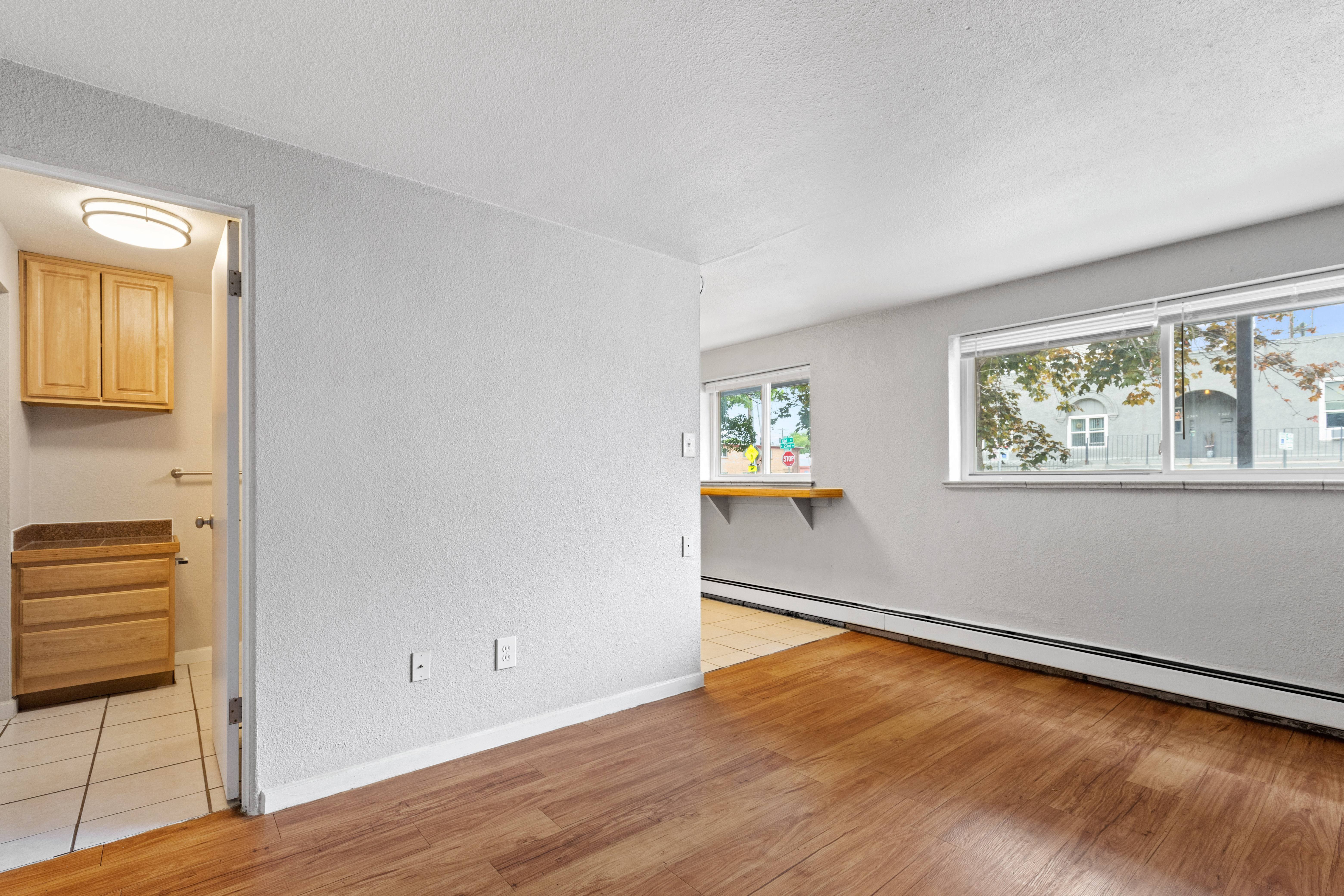 the living room and dining room of an empty house with wood floors and a window